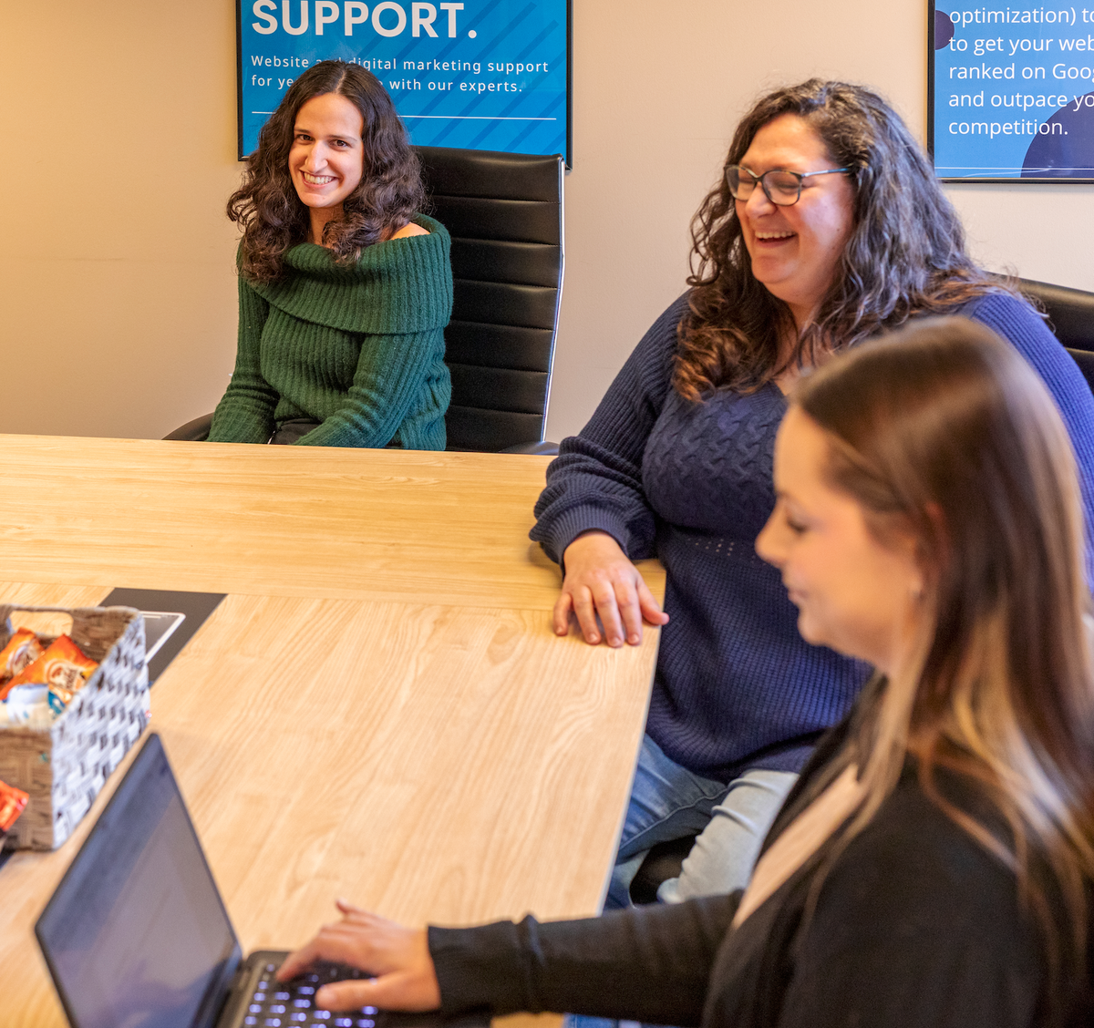three business women in a meeting smiling and talking